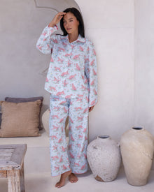 Layla Blue Long PJ Set – full-length view of model standing with hand raised to forehead, wearing pale blue long pyjama set with all-over pink leopard print and pink contrast piping