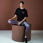 Person sitting on a brown cylindrical stool against a brown background
