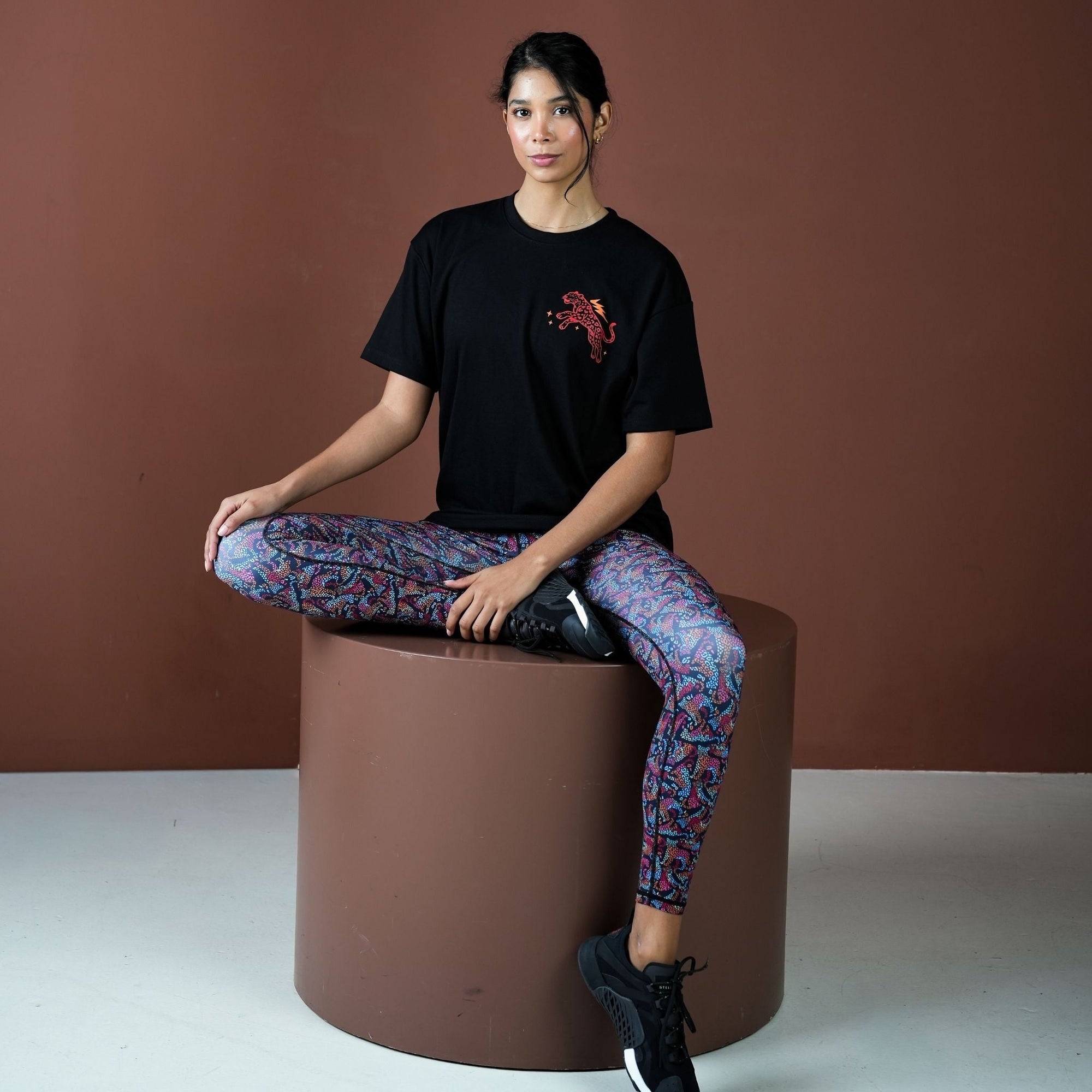 Person sitting on a brown cylindrical stool against a brown background