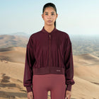 Person wearing a maroon tracksuit with a desert landscape in the background