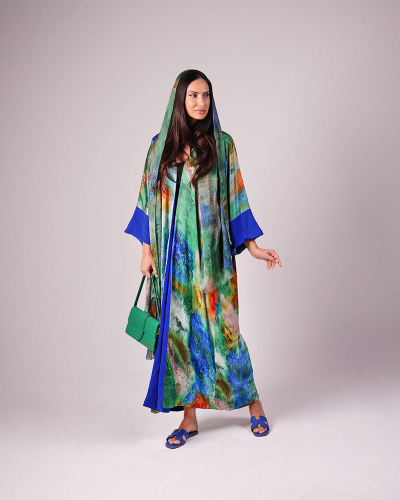 Model wearing the full-length emerald green and cobalt blue printed abaya with a matching headscarf.