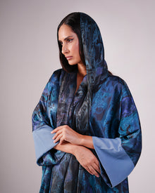 Upper-body view showing the blue patterned fabric, headscarf and pale blue cuffs.