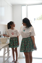 Woman and child wearing the EOS x Rémy Bloom oversized white cotton T-shirt, front view with embroidered chest graphic