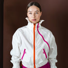 Person wearing a white jacket with pink accents on a brown background