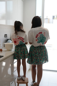 Woman and child wearing the EOS x Remy Bloom oversized white cotton T-shirt, back view with floral graphic artwork.
