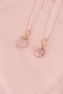 Close-up of the Hazar Azhari Cascading Ruffle Linen Maxi Dress showing the natural Rose Quartz stone detailing.
