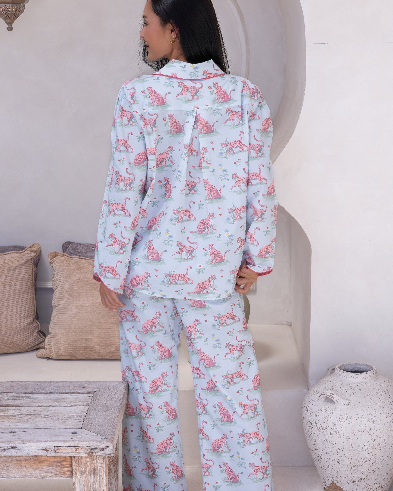 Layla Blue Long PJ Set – back view of model standing in pale blue long pyjama set showing pink leopard print shirt with centre pleat detail and wide-leg trousers with pink piping trim