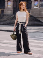 Model posing in the middle of the pedestrian lane, wearing the Aether Linen Trouser in black