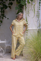 Model wearing the Love Letters x Nour Pyjama Set with a yellow floral print, relaxed short-sleeve shirt and wide-leg trousers.