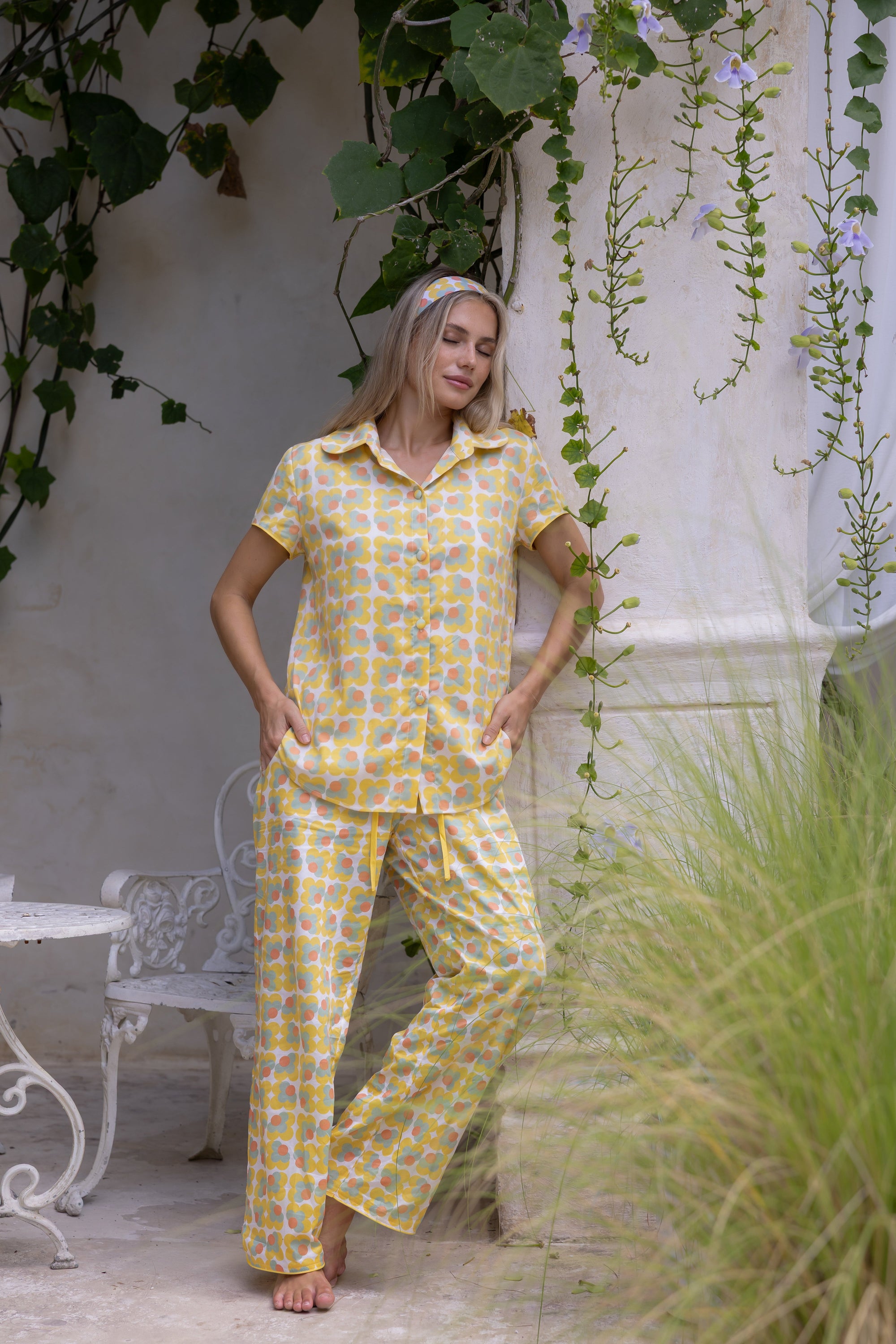 Model wearing the Love Letters x Nour Pyjama Set with a yellow floral print, relaxed short-sleeve shirt and wide-leg trousers.