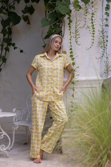 Model wearing the Love Letters x Nour Pyjama Set with a yellow floral print, relaxed short-sleeve shirt and wide-leg trousers.