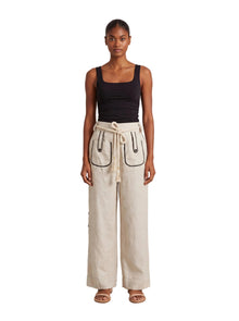 Model is wearing the Aether Linen Trouser in Beige by Muda Clothing
