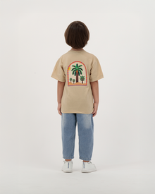 Child wearing The Palm Kids T-Shirt with palm leaf illustration.