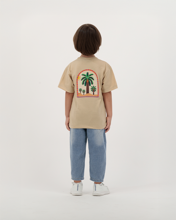 Child wearing The Palm Kids T-Shirt with palm leaf illustration.