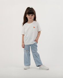 Child dressed in white Batikh Watermelon Print T-Shirt with playful fruit design.