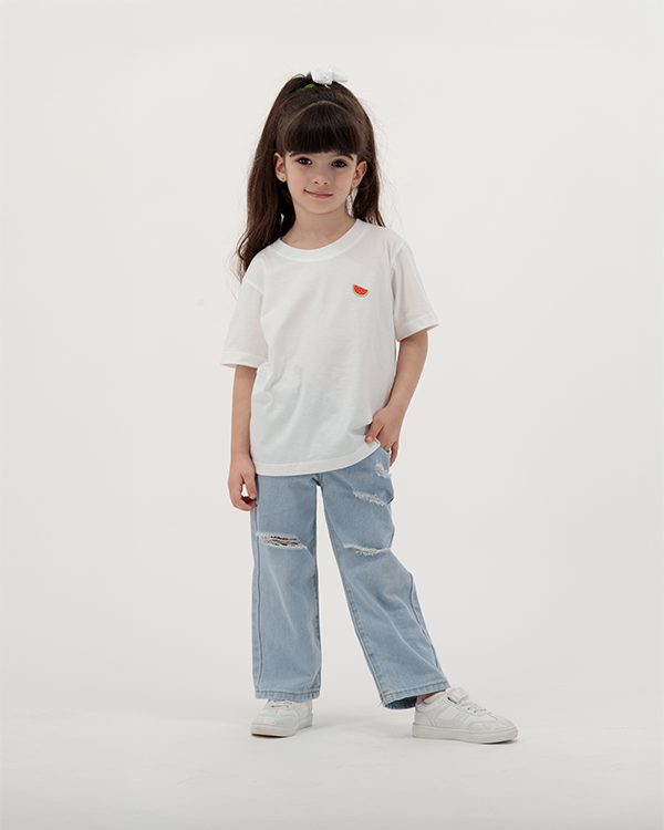 Child dressed in white Batikh Watermelon Print T-Shirt with playful fruit design.