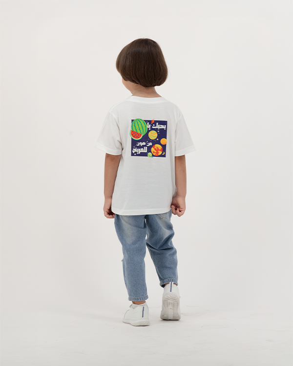 Boy dressed in white Batikh T-Shirt with playful fruit graphic on back.