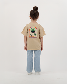 Girl modeling The Palm Kids beige T-Shirt featuring colorful palm print.