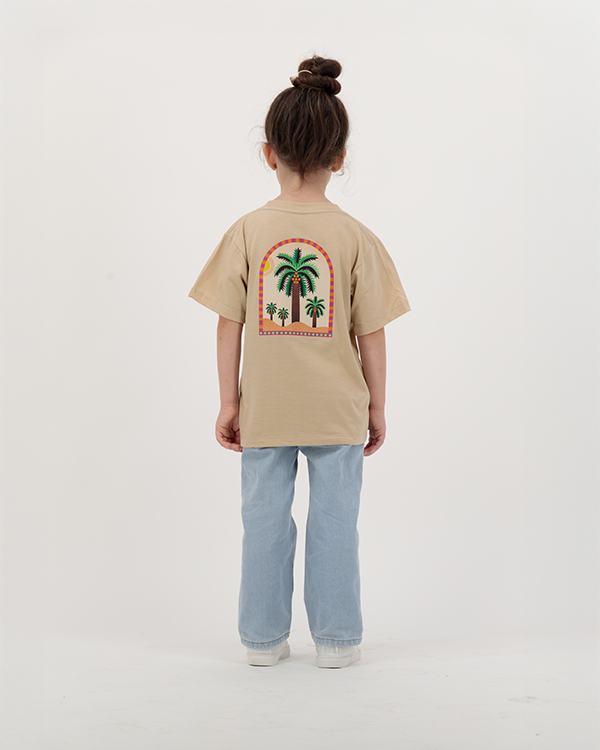 Girl modeling The Palm Kids beige T-Shirt featuring colorful palm print.
