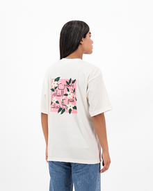 Woman dressed in white Jasmine T-Shirt with floral design on back.
