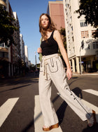 Model crossing the street, wearing the Aether Linen Trouser in beige by Muda Clothing 