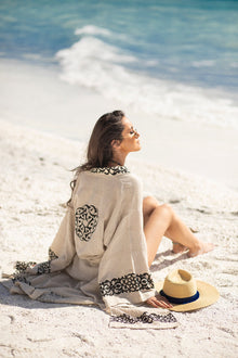 Model sitting on the sand wearing the Gaia Kimono by Zerla Studio